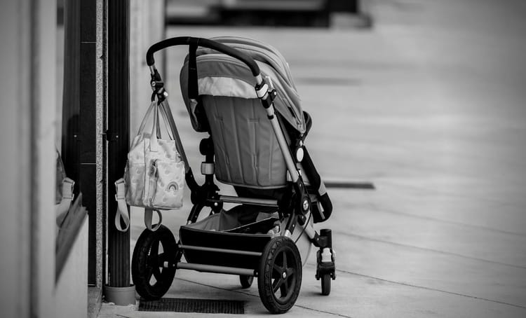 Poussette abandonnée dans un espace public, près d'une vitrine.