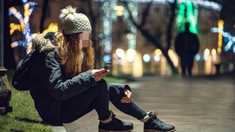 Incroyable : Femmes sans-abri algériennes dans les rues d'Europe et Emirats Jeune femme sans-abri utilisant son téléphone dans un parc illuminé.