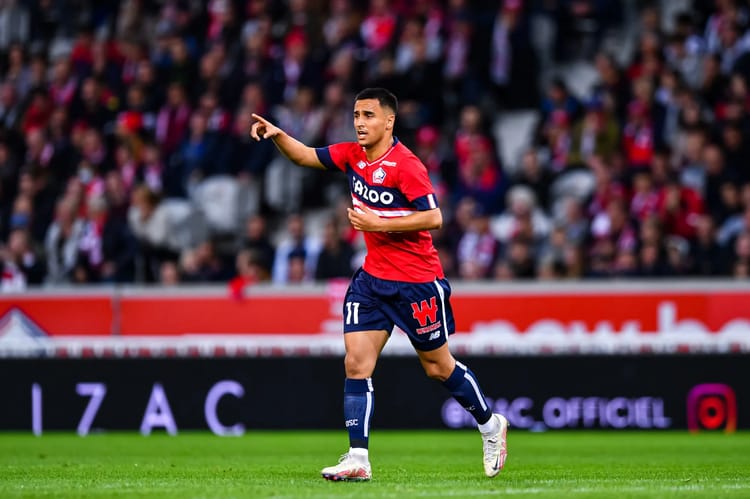 Footballeur en maillot rouge et bleu sur le terrain.