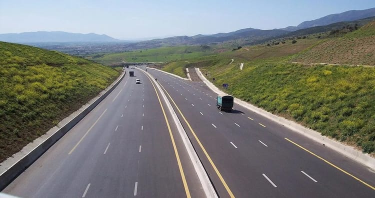 Autoroute en Algérie avec paysage de montagnes et de verdure.