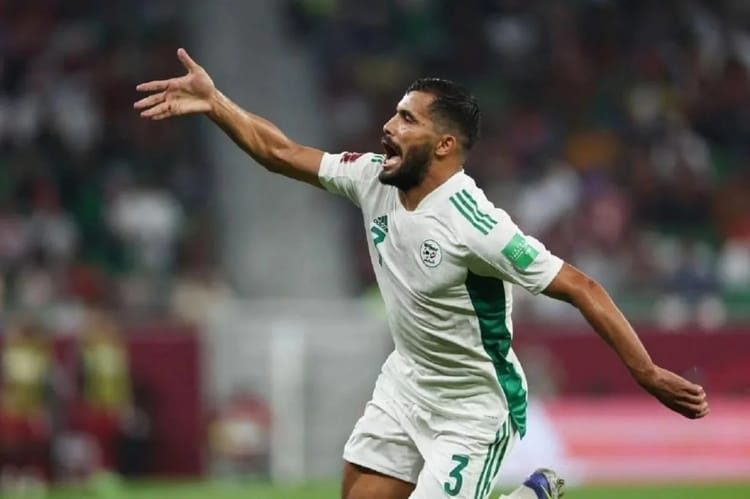 Joueur de football algérien célébrant un but sur le terrain.
