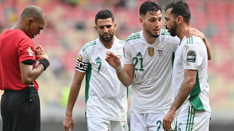 Mahrez et Bensebaini discutent sur le terrain de football.