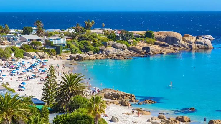 Plage tropicale avec sable blanc, palmiers et eaux turquoise.