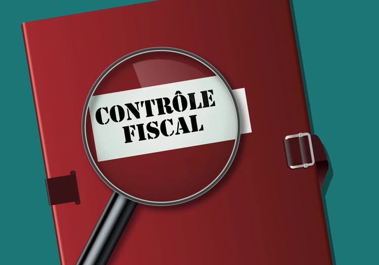 Loupe sur un carnet rouge avec 'Contrôle Fiscal' écrit dessus.