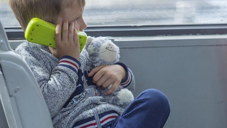 Jeune garçon de 7 ans parlant au téléphone avec une mère à la gare.