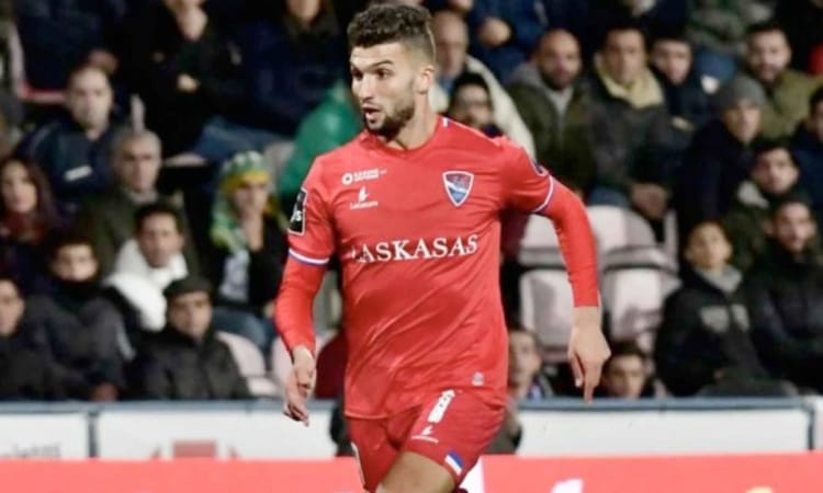 Algérie : Un autre Vert revient au pays Joueur de football en action sur le terrain avec spectateurs en arrière-plan.