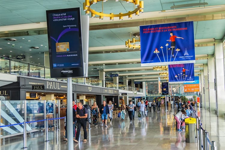 Avis aux voyageurs Algériens : Une grève de grande ampleur s'annonce pour les vols Algérie -France Aéroport animé avec voyageurs et affiches publicitaires colorées.