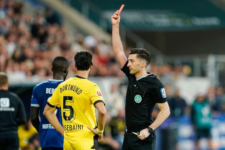 Arbitre montrant un carton rouge à Ramy Bensebaini lors d'un match de football.