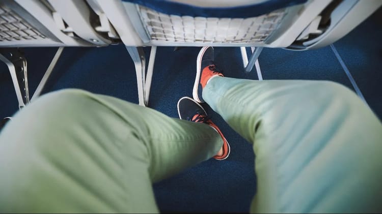 Pourquoi vous ne devriez jamais retirer vos chaussures en avion : les avertissements d'un steward Voyageur en avion avec chaussures retirées, assis en classe économique.