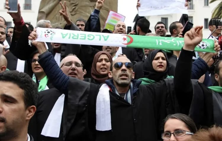 Manifestants algériens avec drapeau et slogans lors d'une protestation.