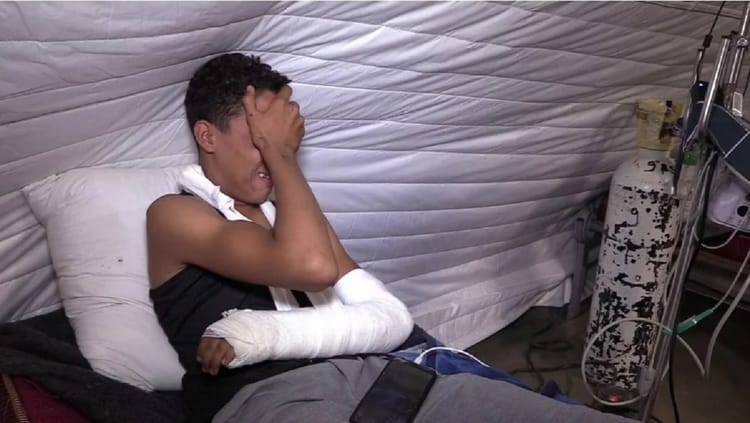 Jeune garçon avec bras en écharpe dans une tente de secours.