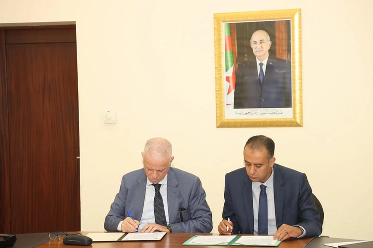 Deux hommes signent un document lors d'une réunion officielle en Algérie.