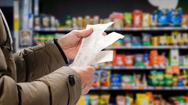 Personne tenant un ticket de caisse dans un supermarché.