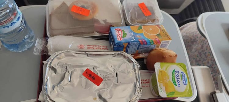 Repas d'avion avec boisson, dessert et snack.