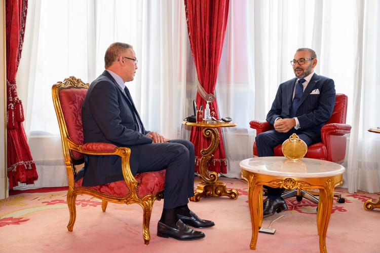 Mohammed VI désigne Fouzi Lekjaa Président du "Comité Coupe du Monde 2030" Deux hommes en costume discutent dans un salon élégant.