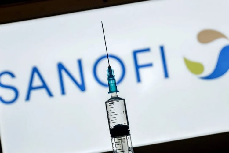 Syringe avec insuline devant le logo Sanofi en arrière-plan.
