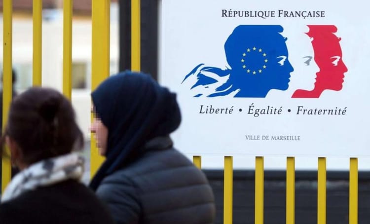 Affaire de Fraude : Un homme accusé d'avoir reconnu faussement la paternité de 17 enfants en France Deux femmes discutant devant un panneau de la République française.