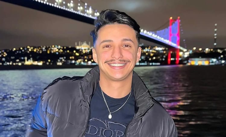 Jeune homme souriant près du pont illuminé à Istanbul.