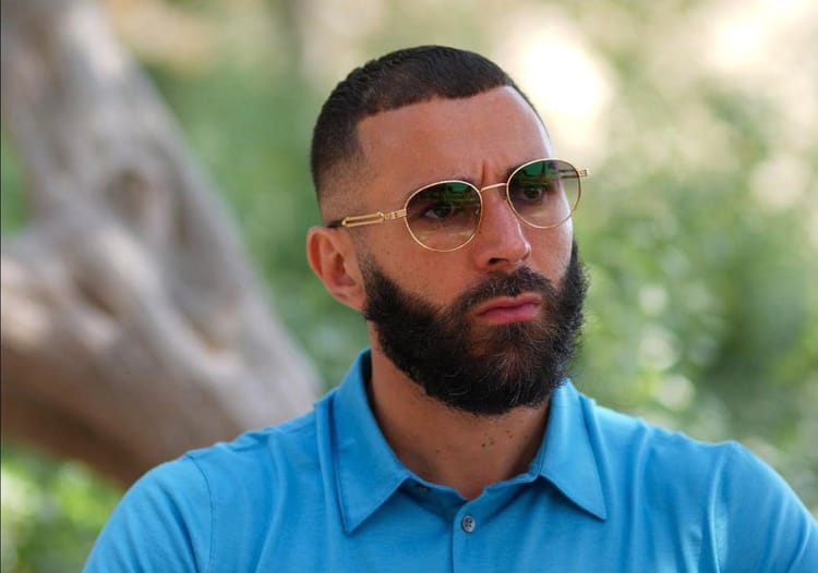Homme portant lunettes de soleil et chemise bleue.