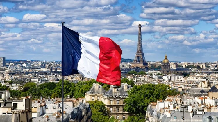 Drapeau français flottant avec la Tour Eiffel en arrière-plan.