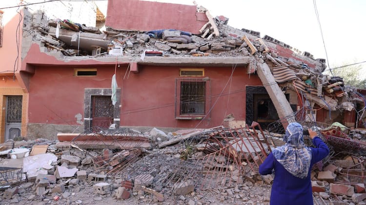 Dame observant une maison endommagée par le séisme à Marrakech.