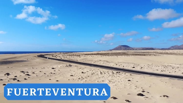 Espagne: A la découverte de l'île de Fuerteventura, une merveille insoupçonnée Plage de Fuerteventura avec ciel bleu et montagnes en arrière-plan.