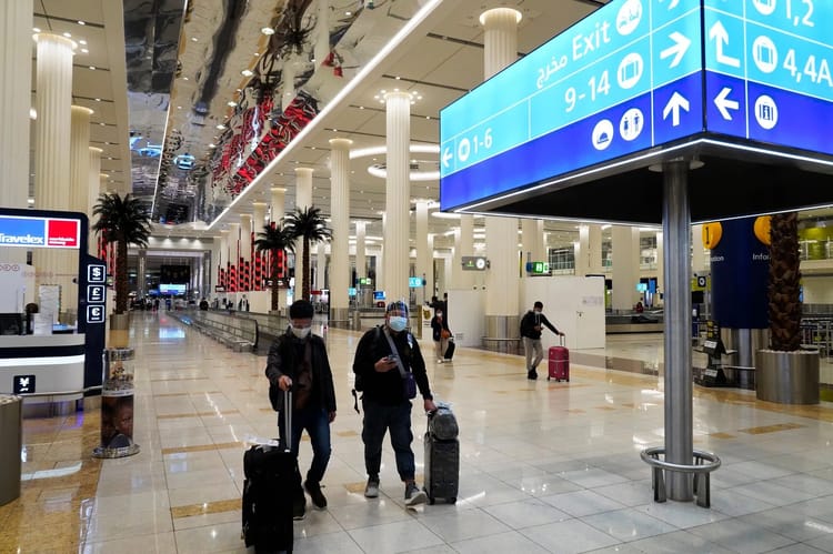 Voyageurs avec valises à l'aéroport de Dubai, intérieur moderne et spacieux.