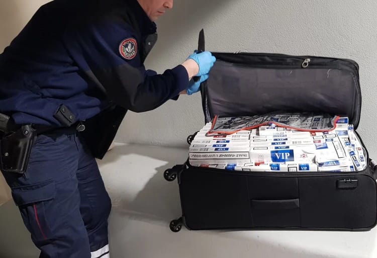Agent de sécurité manipulant des paquets dans une valise ouverte.