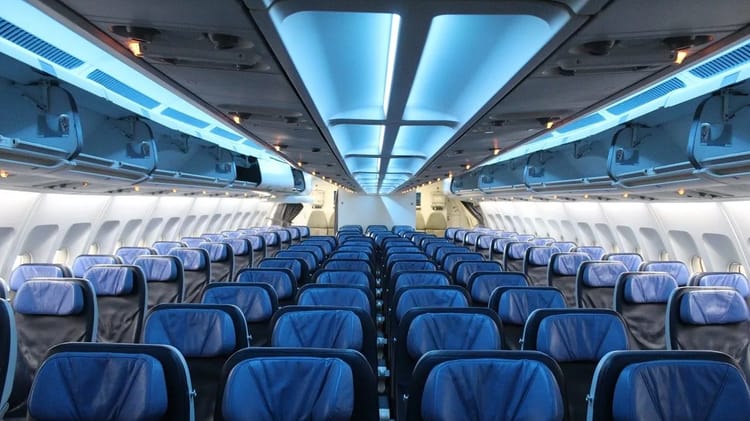Cabine d'avion vide avec sièges bleus et éclairage moderne.