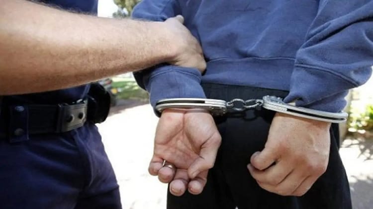 Homme en garde à vue avec mains menottées par un officier de police.