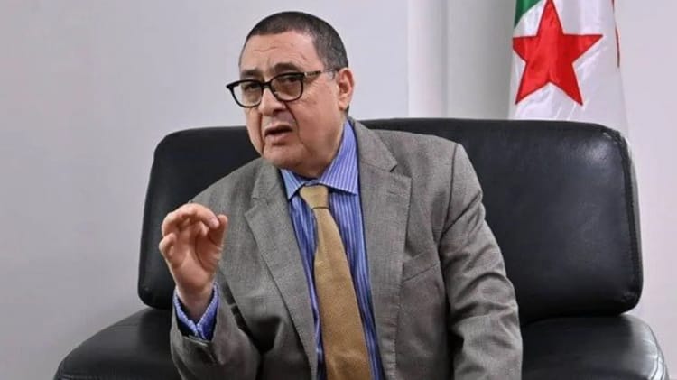Homme en costume parlant lors d'une réunion officielle en Algérie.