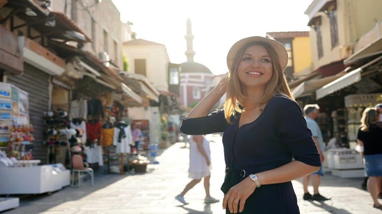 Femme souriante à Oran, marché animé avec boutiques colorées.