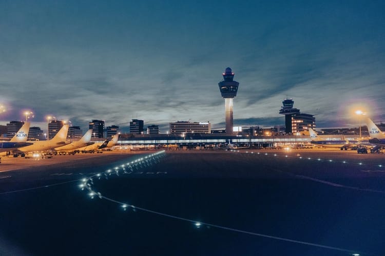 Vue nocturne de l'aéroport avec avions et tour de contrôle.