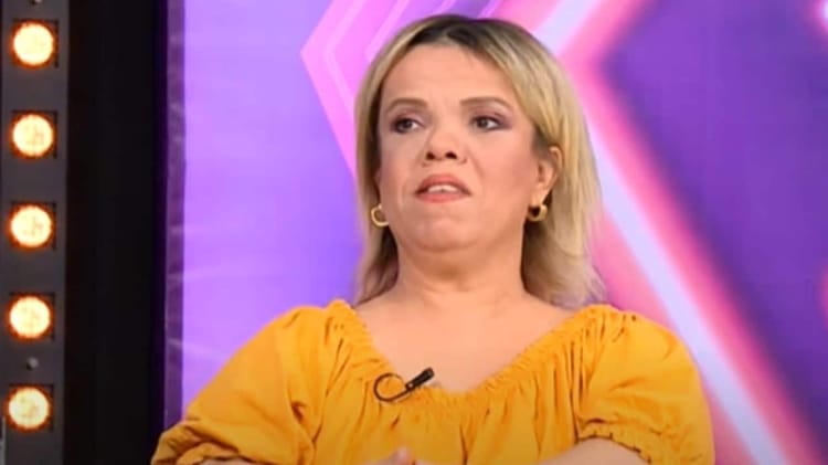 Atika Toubal en interview, portant une robe jaune, exprimant une émotion forte.