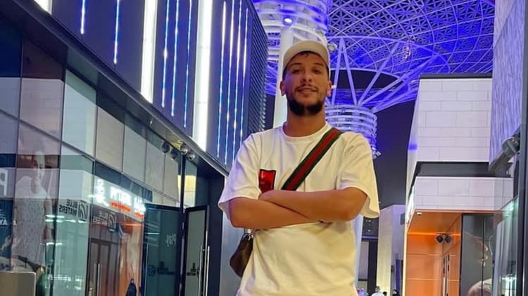 Djalil Palermo dénonce une faute médicale après la perte tragique de sa Belle-sœure Jeune homme portant un t-shirt blanc et un sac à l'épaule dans un centre commercial.