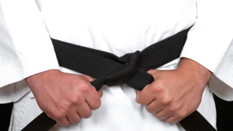 Dihia Chikhi en kimono de karaté avec ceinture noire.