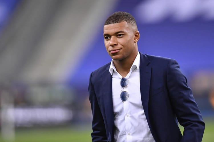Kylian Mbappé : Mystère et rumeurs autour de sa vie amoureuse Kylian Mbappé portant un costume lors d'un événement sportif.