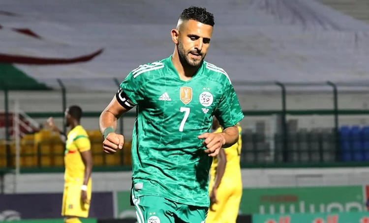 Riyad Mahrez portant le maillot de l'Algérie, en pleine course sur le terrain.