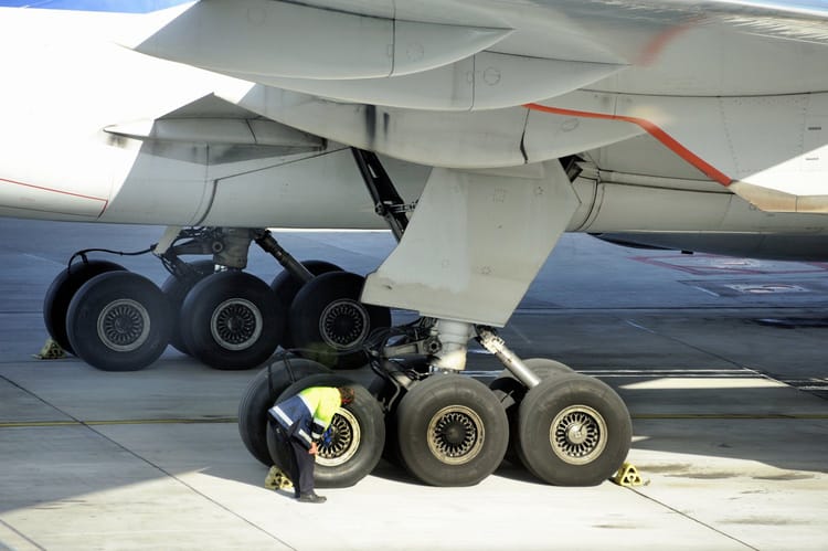 Technicien vérifiant les roues d'un avion au sol.