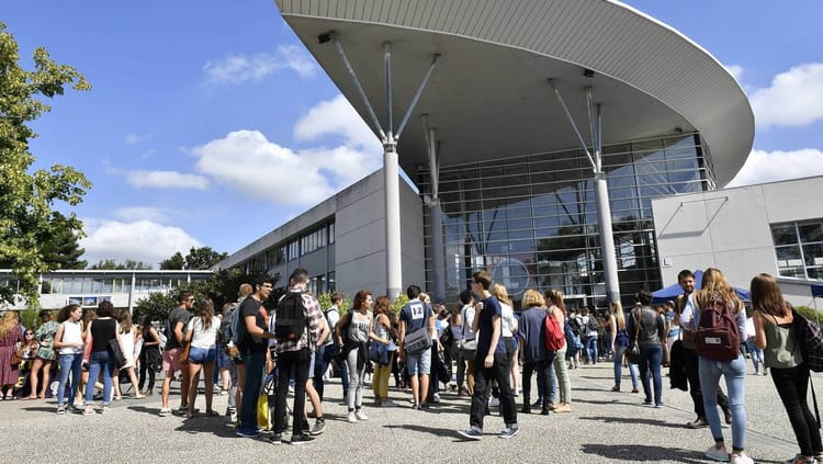Groupe d'étudiants marocains devant une université moderne en plein jour.