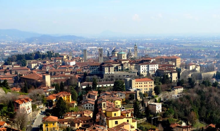 Vue de Bergame avec ses bâtiments historiques et ses collines environnantes.