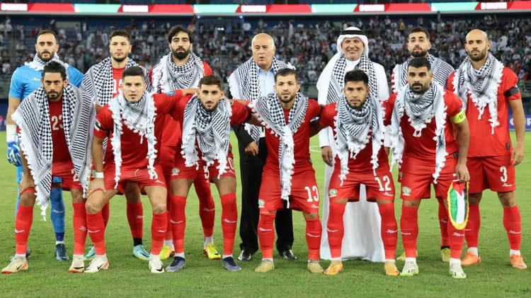 Groupe de joueurs de football algériens en tenue rouge et foulards noirs et blancs.