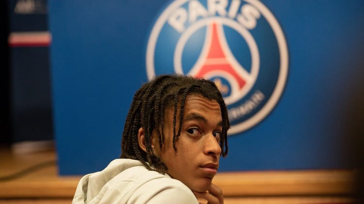 Jeune joueur de football devant le logo du PSG.