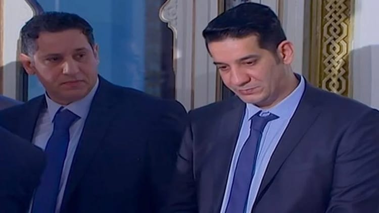 Deux hommes en costume lors d'une réunion officielle.