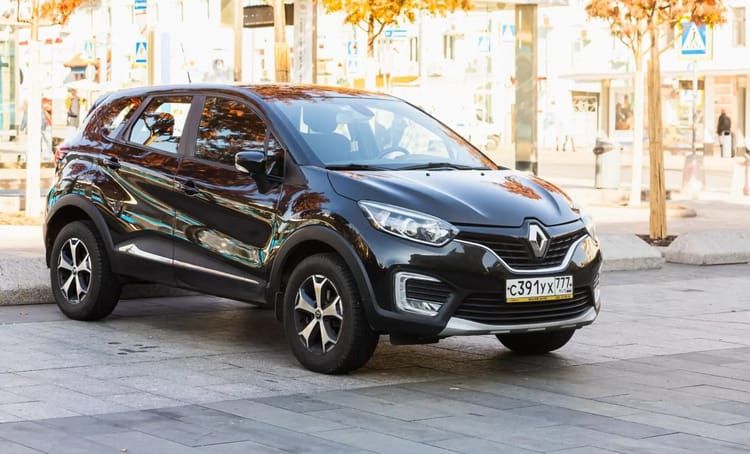 Location de voiture à moindre coût : Voici quelques astuces utiles Voiture Renault noire stationnée en centre-ville avec arbres en arrière-plan.