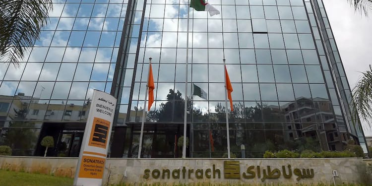 Façade en verre du siège de Sonatrach avec drapeaux algériens.