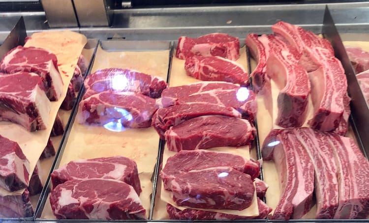 Différents morceaux de viande rouge fraîche en vitrine de boucherie.