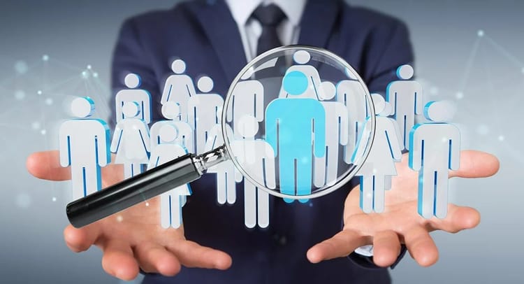 Magnifying glass sur un groupe de silhouettes humaines pour le recrutement.