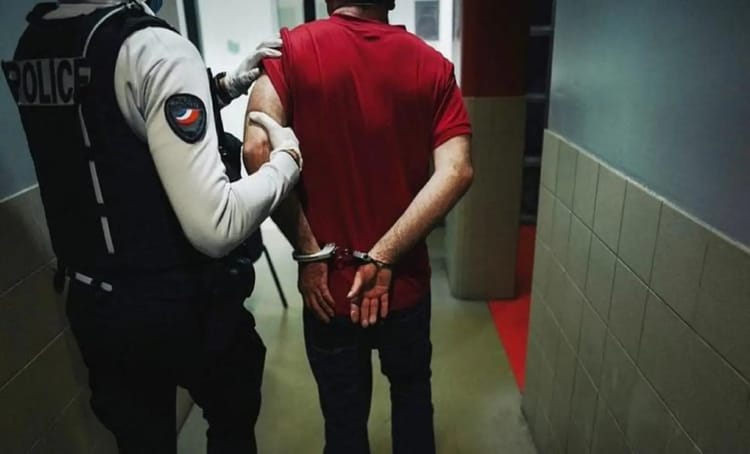 Policier menottant un homme dans un couloir à Paris.