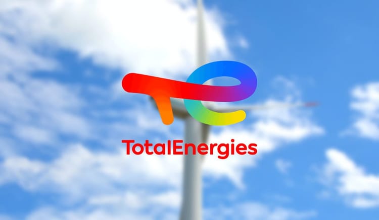 Logo de TotalEnergies contre un ciel bleu avec nuages blancs.
